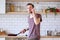 Photo of brunet man with frying pan in his hands talking on phone in kitchen