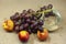 Photo of a brush of grapes with nectarine with a glass on a beige background