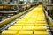 Photo of a busy conveyor belt filled with yellow containers. Industrial cheese production plant. Modern technologies. Production