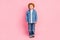 Photo of calm concentrated ginger little kid posing wear denim jacket jeans shoes  pink color background