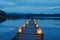 A photo capturing a long dock adorned with floating lanterns, A private jetty extending into a calm lake at twilight, lined with