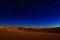 A photo capturing the night sky filled with stars shining above a vast desert landscape, A golden desert under a starry night sky