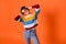 Photo of carefree funny young lady dressed striped pullover dark glasses arms head dancing isolated orange color