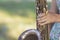 photo central part of saxophone in hands of young woman in summer