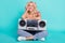 Photo of charming dreamt young lady wear striped t-shirt sitting floor listening boom box smiling isolated turquoise