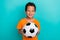 Photo of charming excited small man wear yellow t-shirt smiling catching football ball  turquoise color