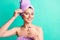 Photo of charming girl hold bottle pipette apply essence face wear purple towel turban isolated turquoise color