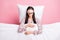 Photo of charming sweet young woman sleepwear mask lying pillow covering duvet isolated pink color background