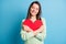 Photo of charming young lady embrace red paper heart closed eyes wear green pullover isolated blue color background