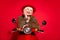 Photo of cheerful aged woman happy positive smile drive bike trip hand touch cheek isolated over red color background