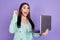 Photo of cheerful amazed young woman hold laptop winner good mood isolated on violet color background