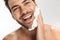 Photo of cheerful half-naked man applying shaving foam and smiling