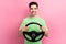 Photo of cheerful handsome young guy driving steering wheel enjoying comfort volkswagen ag automobile isolated on pink