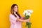 Photo of cheerful happy woman hold hands flowers give empty space holiday isolated on yellow color background