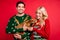 Photo of cheerful positive couple hold little cute dog wear ugly ornament pullover isolated red color background