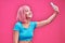 Photo of cheerful positive cute pretty attractive woman with pink hair taking selfie smiling toothily isolated over pink