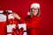 Photo of cheerful positive grandma prepare presents stack shop wear specs hat pullover isolated red color background
