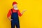 Photo of cheerful positive senior guy dressed uniform overall red hardhat looking holding arm empty space 