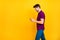 Photo of cheerful positive trendy white man browsing through his telephone talking with friends wearing blue pants