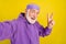 Photo of cheerful retired man have fun take selfie show cool v-symbol isolated over yellow color background