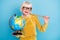 Photo of cheerful short hairdo aged lady hold stick globe wear eyewear blouse isolated on blue color background