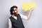 Photo of cheerful young hipster guy holding epmty yellow speech bubble