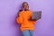 Photo of cheery young woman use online banking laptop dressed trendy autumn orange knitwear pullover isolated on purple