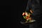 In the photo, the chef is holding a black frying pan with red fish and vegetables in his hand. Levitation. Black background. Place