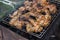 Photo of chicken wings in tomato sauce, roasting in the grill rack on charcoal grill in hiking picnic. Selective focus