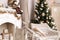 Photo with Christmas decor in natural beige colors, an artificial fireplace with gifts, two armchairs and decorated Christmas