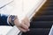 The photo close up of businessman watching his watch in his hand while standing on the escalator.  Business and finance concept