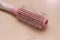 Photo close up top view hair fall at white pink plastick comb at wooden table