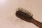 Photo close up top view hair fall at white pink plastick comb at wooden table