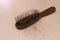 Photo close up top view hair fall at white pink plastick comb at wooden table