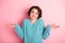 Photo of clueless funny young lady look camera shrug shoulders wear blue sweater isolated pink background