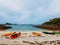 Photo of colorful kayaks on the sandy seashore, hills, blue sky in Norway.