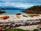 Photo of colorful kayaks on the sandy seashore, hills, blue sky in Norway.