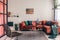 photo of a comfy living room interior with a round table on gray rug, wicker armchair and red corner sofa