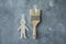 Photo of concept of house repair, paper cut man and wall paint brush sticking with adhesive tape on gray smeared plaster