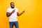 Photo of confident cheerful black person pointing at yellow background he has been isolated with