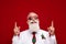 Photo of confident funny man dressed white christmas costume glasses pointing fingers up empty space isolated red color