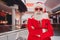 Photo of confident funny santa folded arms prepare x-mas gifts wear sunglass hat red tuxedo in supermarket mall center