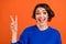 Photo of cool brunette millennial lady show v-sign wear blue pullover isolated on orange color background