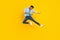 Photo of cool funny dark skin guy dressed denim shirt practicing karate jumping high isolated yellow color background