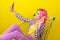 Photo of cool pink hairdo young lady do selfie sit in trolley wear shirt isolated on yellow background