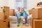 Photo of couple sitting on couch and drinking shampagne among cardboard boxes