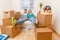 Photo of couple sitting on couch with laptop among cardboard boxes