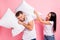 Photo of crazy casual couple destroying each other with pillow while isolated with pink background