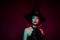 Photo of cruel evil mysterious woman wear gothic witch dress headwear look back space isolated red fog color background