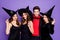 Photo of cruel witch ladies and warlock guy ready for halloween student event wear black dresses hats and vampire cloak